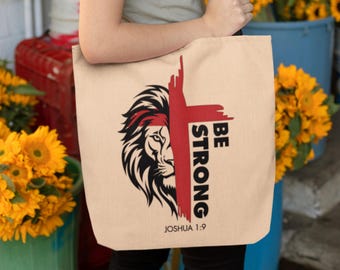 May include: A beige canvas tote bag with a red and black lion graphic and the text "Be Strong Joshua 1:9".