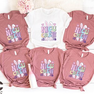 May include: Five pink t-shirts with a pastel colored bunny graphic and the text "NICU CREW".