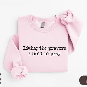 a pink shirt with a saying saying living the prayers i used to pray