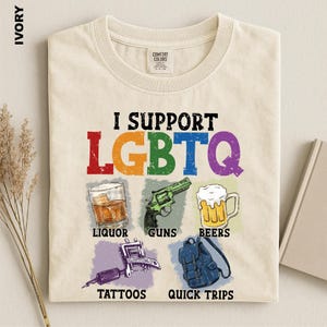 May include: An ivory t-shirt featuring the text I SUPPORT LGBTQ in rainbow colors. Below are five illustrations with labels: a glass of liquor, a green revolver labeled GUNS, a beer mug labeled BEERS, a tattoo machine labeled TATTOOS, and a blue backpack labeled QUICK TRIPS.