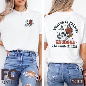 May include: White t-shirt with a skull and flowers graphic on the front and the text "I believe in holding grudges I'll heal in hell" on the back.