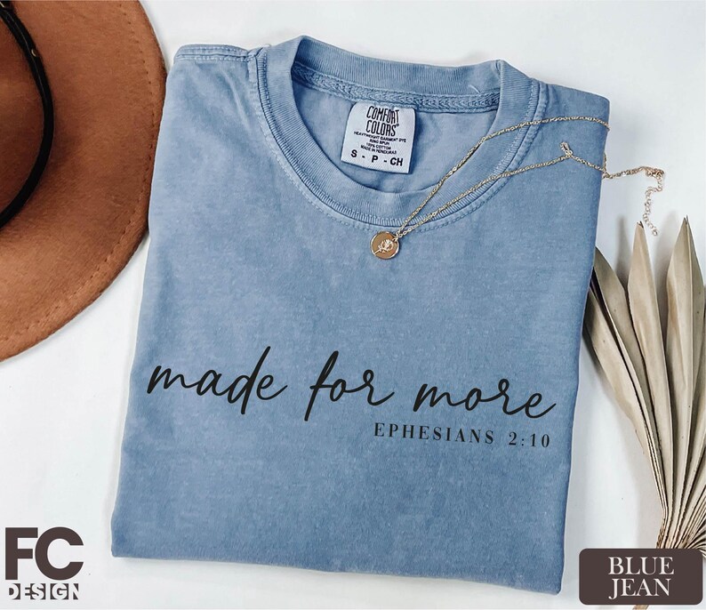 a blue t-shirt with the text "made for more" printed on it, along with a necklace and a hat.