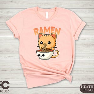 a women's t - shirt with a cat in a cup reading ramen