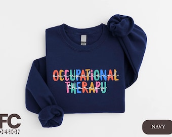 Op de afbeelding: Donkerblauwe trui met de tekst "OCCUPATIONAL THERAPY" in kleurrijke letters.