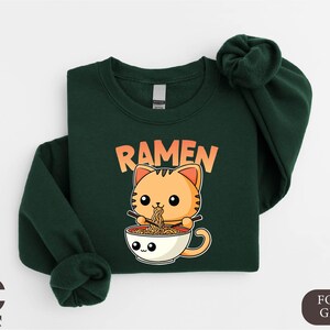 a green shirt with a cat in a cup of ramen