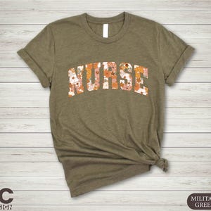 May include: A green t-shirt with the word "NURSE" in floral print letters. The shirt is made of a soft, comfortable material.