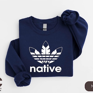 May include: A navy blue sweatshirt with a white stylized feather design resembling the Adidas logo and the word "native" below it.