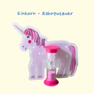 Könnte beinhalten: Ein rosa-weißes Zahnbürsten-Timer in Einhornform mit dem Text "Einhorn - Zahnputzuhr". Der Timer ist eine rosa Sanduhr, die Kindern helfen soll, ihre Zähne für die empfohlene Zeit zu putzen. Der Hintergrund ist hellgelb.