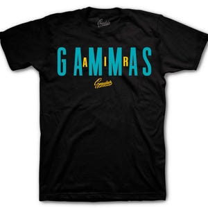 May include: Black t-shirt with the word "GAMMAS" in teal and yellow letters. The shirt has a crew neck and a small logo above and below the text. The shirt is made of a soft material.