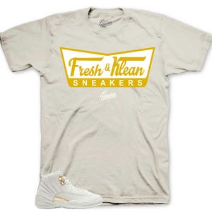 May include: A pair of white sneakers with gold accents and a white t-shirt with a gold logo that says "Fresh & Klean Sneakers".
