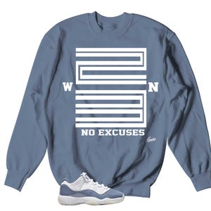 May include: A blue sweatshirt with a white graphic of the number 23 with the letters W and N on either side of the number. The text "NO EXCUSES" is below the number. A pair of white and blue sneakers are in the bottom of the image.