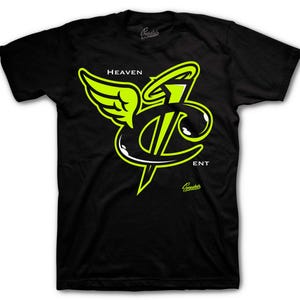 May include: Black t-shirt with a neon green and white graphic design. The design includes the words "HEAVEN ENT" and a stylized logo with wings. The shirt is made of a soft material.