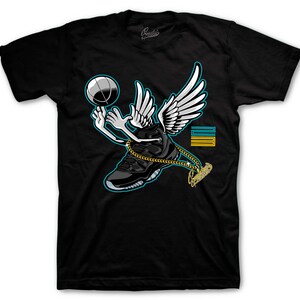 May include: Black t-shirt featuring a cartoon sneaker with wings, a basketball, and a gold chain. The sneaker is black with a light blue trim. The wings are white. The design includes the text "Sneakers".