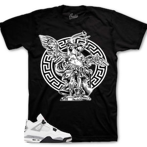 Op de afbeelding: Zwart T-shirt met een gedetailleerde afbeelding van een engel met vleugels, een zwaard en een schild, tegen een wit cirkelvormig ontwerp. Witte en grijze sneakers met zwarte accenten staan op de voorgrond.