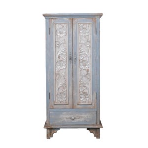 Op de afbeelding: Een lichtblauwe houten kast met gesneden bloemmotieven op de deuren. De kast heeft een enkele lade en decoratieve handgrepen. De kast is een opbergmeubel, geschikt voor een slaapkamer of woonkamer. Afmetingen in centimeters.