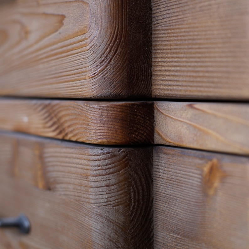 May include: Close-up of a wooden drawer with a natural wood finish. The drawer is made of multiple pieces of wood that are joined together. The wood grain is visible and the drawer has a rustic look.