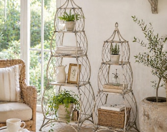 May include: Two ornate, antique-style metal shelves with a cage-like design. Each shelf has three tiers, holding potted plants, books, and decorative items. The shelves are painted in a distressed white finish, adding to their vintage appeal.