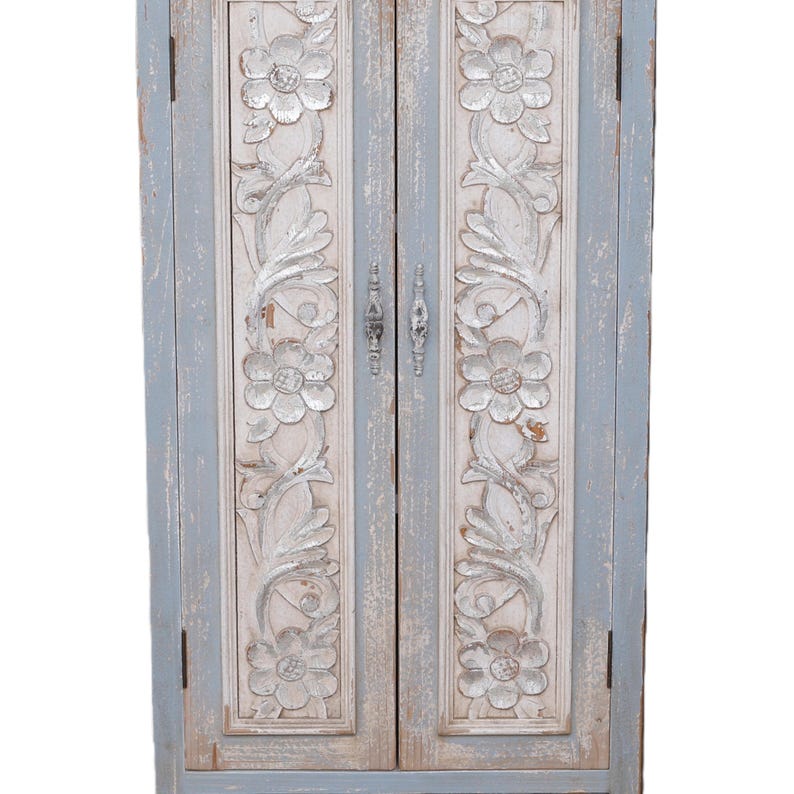 Op de afbeelding: Een kast met twee deuren en een verweerde, lichtblauwe en witte afwerking. De kastdeuren hebben gebeeldhouwde bloemen- en bladerenontwerpen. De hardware is van zilverkleurig metaal. De kast is een decoratief opbergstuk.