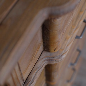 May include: Close-up of a wooden dresser drawer with a carved handle. The drawer is made of dark brown wood with a natural grain pattern.
