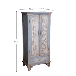 Op de afbeelding: Een blauwe houten kast met gebeeldhouwde bloemendetails op de deuren. De kast is 143 cm hoog, 67 cm breed en 38 cm diep. Het heeft een lade aan de onderkant en een decoratief bovenblad.