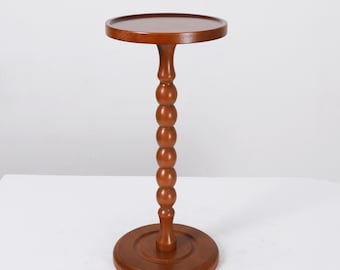Könnte beinhalten: Kleiner, runder Beistelltisch aus Holz mit dunkelbraunem Finish. Der Tisch hat eine runde Tischplatte, eine gedrehte, perlenbesetzte Mittelsäule und einen kreisförmigen Sockel. Der Tisch ist ca. 71 cm hoch und 30 cm im Durchmesser.