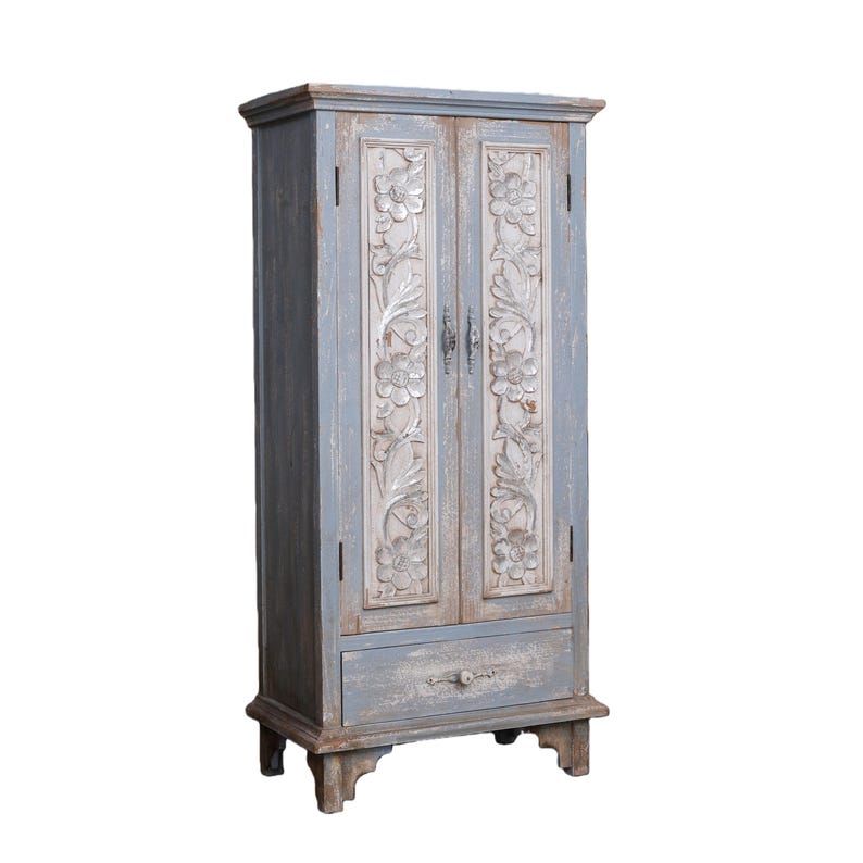 Op de afbeelding: Een hoge, blauw geverfde houten kast met gesneden bloemmotieven op de deuren. De kast heeft een enkele lade aan de onderkant en staat op vier korte poten. De afwerking van de kast heeft een verweerde uitstraling.