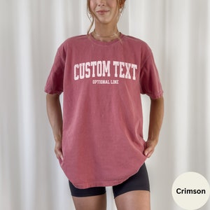 May include: Crimson red oversized t-shirt with white text that reads "CUSTOM TEXT" and "OPTIONAL LINE".