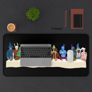 May include: A black desk mat with a white table and a group of cartoon characters sitting around it. The characters are wearing various costumes and hats. A laptop computer is placed on top of the table.