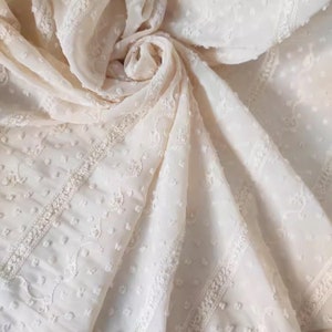 May include: White sheer fabric with a delicate embroidered pattern. The fabric has a textured, slightly raised surface and a subtle sheen.
