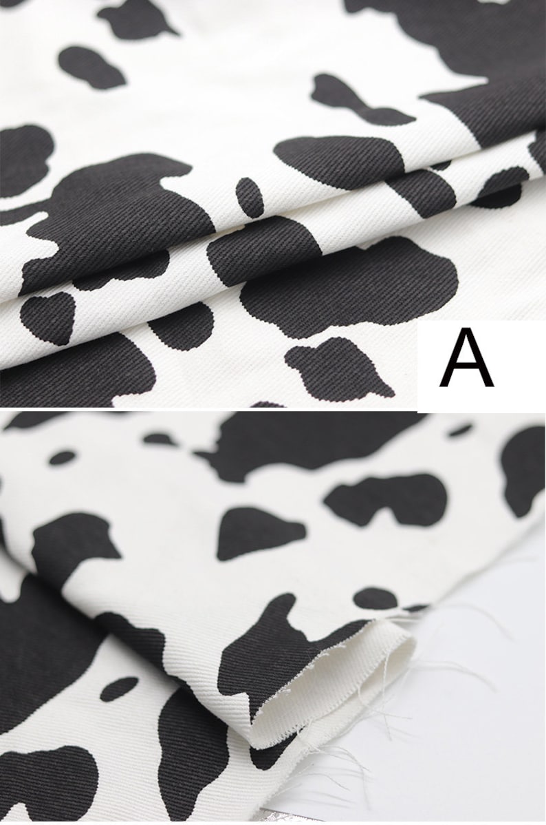 May include: Close-up of white fabric with a black cow print pattern. The fabric is folded over, showing the texture of the material.