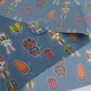 May include: Blue fabric with a repeating pattern of cartoon animals, including rabbits, dogs, and carrots. The fabric is waterproof and has a subtle sheen.