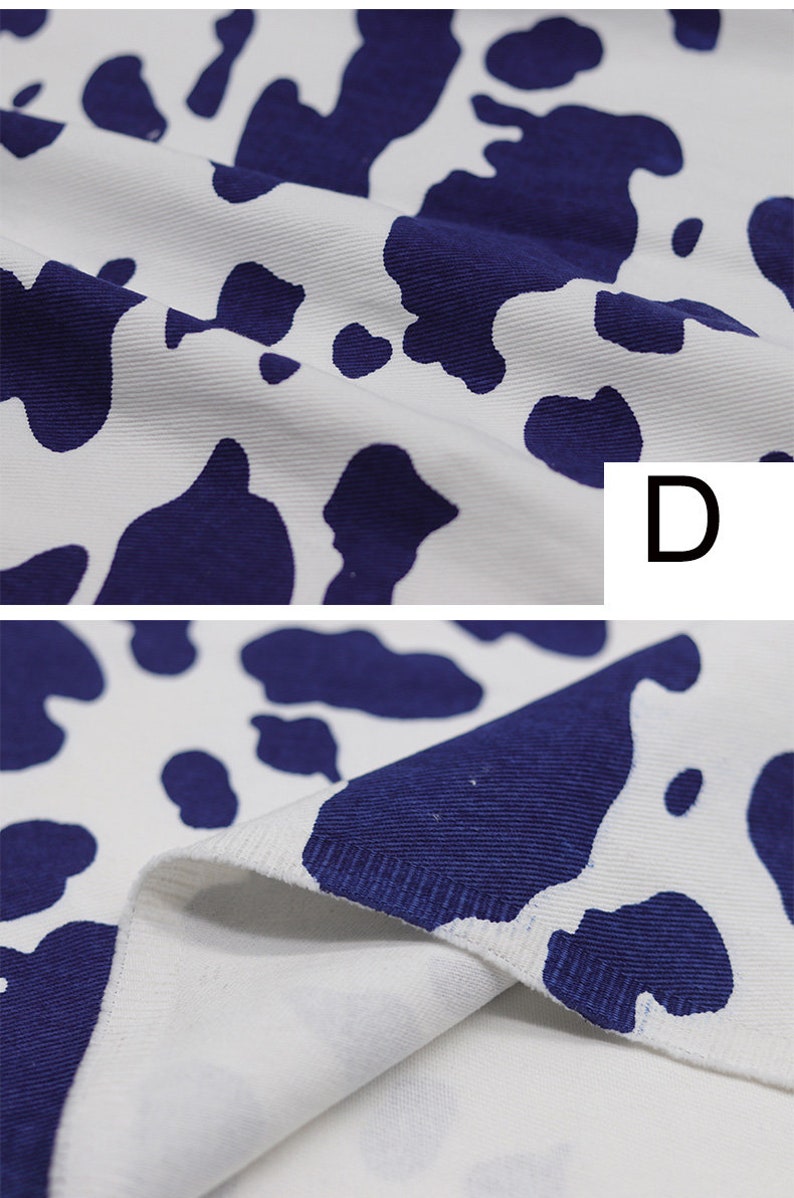 May include: Close-up of white fabric with a blue cow print pattern. The fabric is textured and has a slight sheen. The fabric is folded in half, showing the inside of the fabric.
