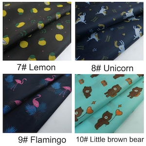 May include: Four fabric swatches with different patterns. The first swatch is black with yellow lemons, the second is navy blue with white unicorns, the third is navy blue with pink flamingos, and the fourth is turquoise blue with brown bears.