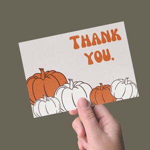 May include: A white card with the text "Thank You." in orange letters. The card is decorated with orange and white pumpkins.