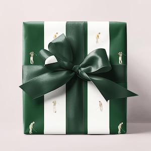 May include: Wrapped gift with green and white striped paper featuring miniature golfers. A dark green satin ribbon and bow are tied around the package. The gift wrap has a golf theme.