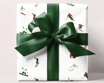 May include: A wrapped gift with white paper featuring skiers and snowboarders in red, green, and gray. The gift is tied with a dark green satin ribbon and bow.