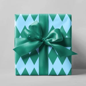 May include: A wrapped gift box with a teal green satin ribbon and bow. The wrapping paper has a light blue and teal green diamond pattern. The gift is presented on a light gray background.