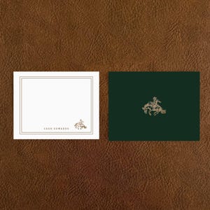 May include: Two square cards on a brown leather background. One white card has a gold border and the text "CASH EDWARDS". The other is dark green with a gold illustration of a person riding a horse.