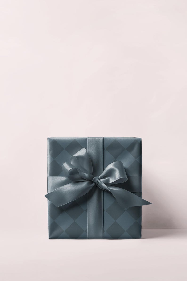 May include: A square gift box wrapped in teal paper with a diamond pattern. A matching teal satin ribbon is tied in a bow on top. The background is a soft pink.