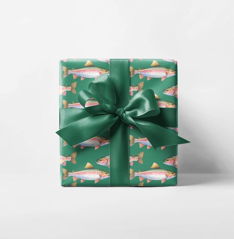 May include: A wrapped gift with green wrapping paper featuring a repeating pattern of watercolor trout. The gift is tied with a dark green satin ribbon and bow. The background is a solid white.