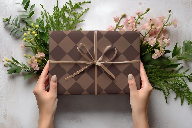 Op de afbeelding: Een bruine en beige cadeaudoos met een ruitpatroon is vastgebonden met een bruin lint. De doos wordt vastgehouden door twee handen.