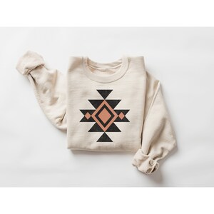 May include: A beige sweatshirt with a black and peach geometric design on the front.