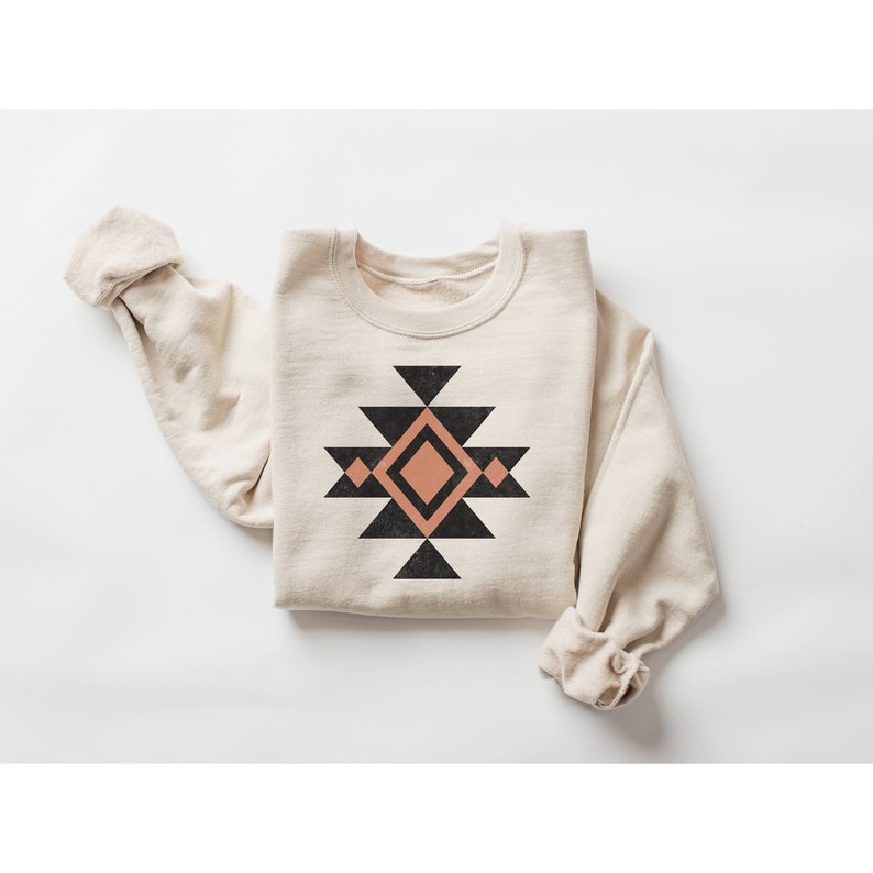 May include: A beige sweatshirt with a black and peach geometric design on the front.