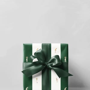 May include: A wrapped gift box with a dark green bow. The gift wrap is dark green with white vertical stripes. Small illustrations of golfers are on the white stripes. The bow is made of dark green satin ribbon.