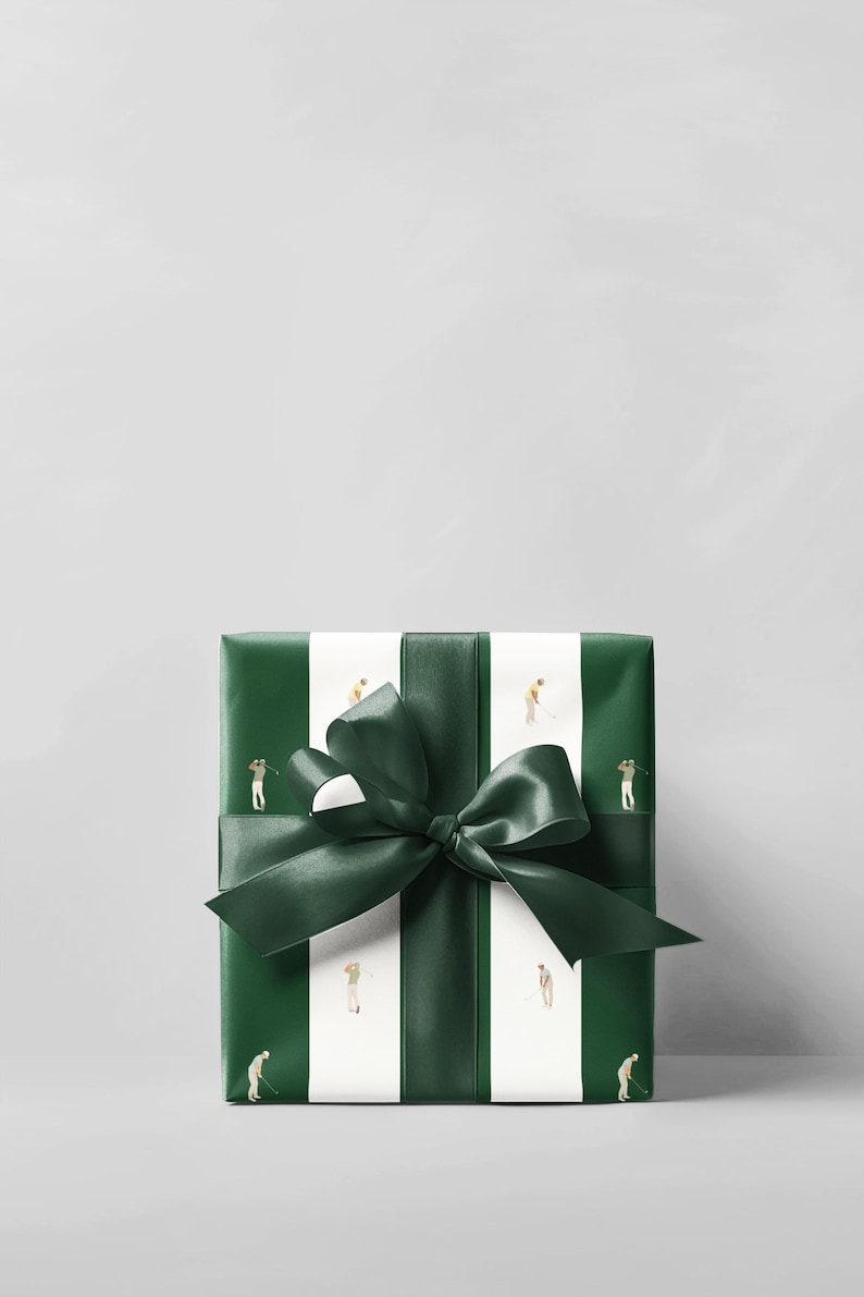May include: A wrapped gift box with a dark green bow. The gift wrap is dark green with white vertical stripes. Small illustrations of golfers are on the white stripes. The bow is made of dark green satin ribbon.