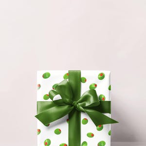 May include: A wrapped gift with white paper featuring a pattern of green olives with red centers. A large, dark green satin ribbon is tied around the package in a bow.