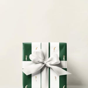 May include: A wrapped gift with green paper featuring white stripes and miniature golfers. A large white bow adorns the package. The gift is presented on a white surface.