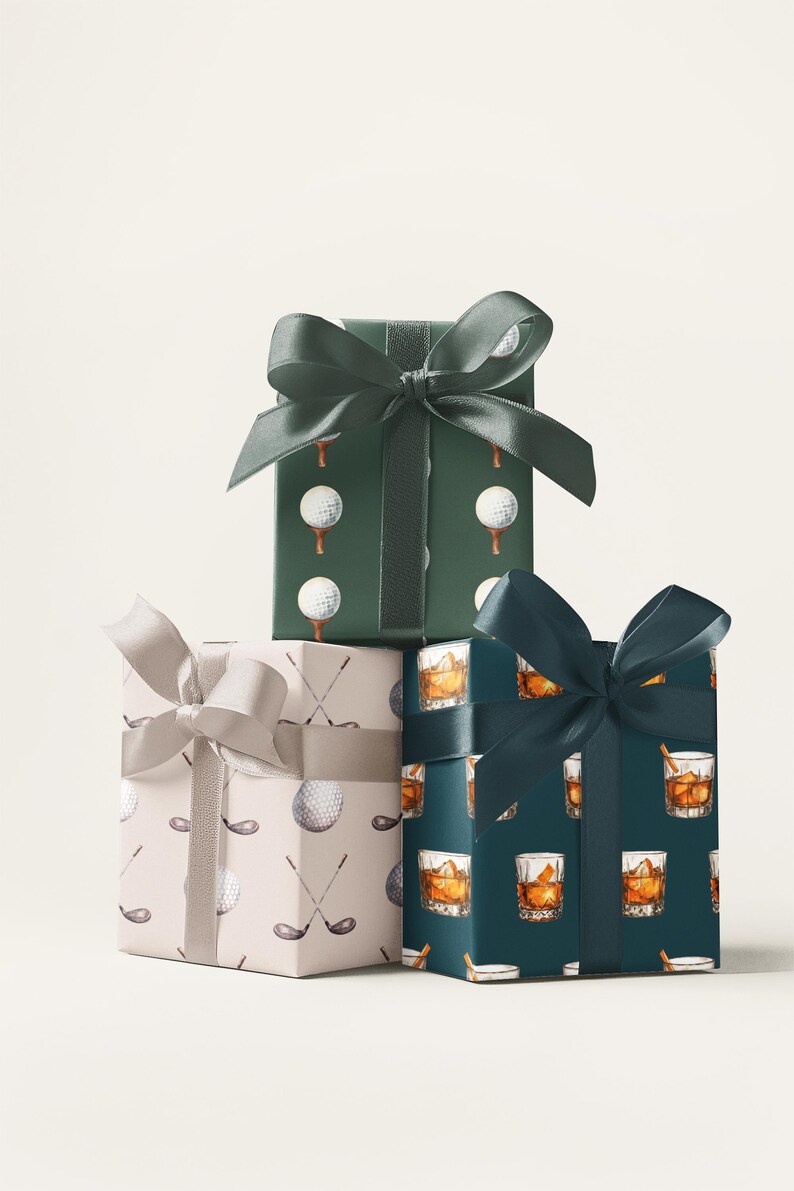 K&ouml;nnte beinhalten: Drei verpackte Geschenkboxen mit dekorativen Schleifen. Die Boxen sind in gemustertes Papier mit Golfb&auml;llen, Golfschl&auml;gern und Whiskeygl&auml;sern verpackt. Die Schleifen sind in Gr&uuml;n- und Silbert&ouml;nen gehalten.