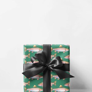May include: A wrapped gift with green wrapping paper featuring a pattern of watercolor trout. The gift is tied with a large black satin bow. The trout are depicted in shades of pink, yellow, and silver, against a green background.