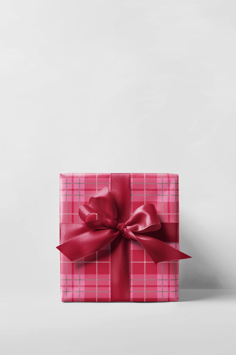 May include: A wrapped gift box with a pink plaid pattern and a deep red satin ribbon and bow. The gift is centered against a white background, creating a clean and festive presentation.